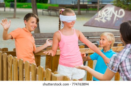 Boys with girlfriends are playing in blindfolders on the playground.