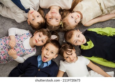 Boys and girls in circle. Happy children having fun. kids lay down together. Happy children lying on the floor in a circle with hands. Top view. Group of children beautiful smile lying on the floor