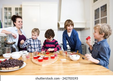 Boys And Girls Decorating Cupcakes At A Kitchen Counter During A Baking Workshop For Kids At A Birthday Party