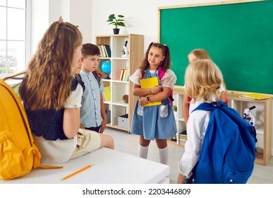 Boys And Girls Elementary School Students Talking Together In School Classroom At Recess. Schoolchildren With Backpacks And Books Discuss Lesson In Modern School. Concept Of Children's Education.