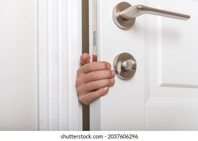 Boys hand sticking out of closed door. Prevent child hazard concept. School kid playing hide and seek game at home or at school.
