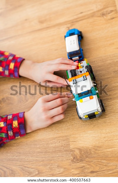 Boy\'s hands move toy\
truck. Child playing with toy vehicle. Technicians need to hurry.\
Power of imagination.