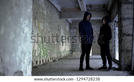 Boys in hoodie talking in ruined building, teenage gang, young criminals