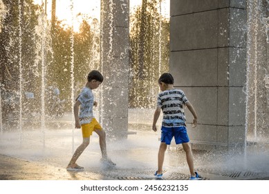 Boys jumping in water fountains. Children playing with a city fountain on hot summer day. Happy friends having fun in fountain. Summer weather. Friendship, lifestyle and vacation. - Powered by Shutterstock