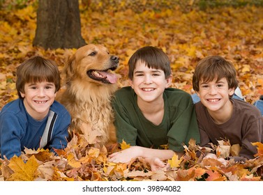 Boys Laying Down With The Dog In The Fall Leaves