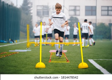 Boys On Agility Training On School Soccer Pitch. Athlete Soccer Player In Training. Young Boy Running Through Ladder And Skipping. Agility Ladder Drills And Ladder Exercises