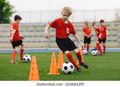 Boys on soccer football training. Young players dribble ball between training cones. Soccer summer training camp. Players on football practice session - Powered by Shutterstock