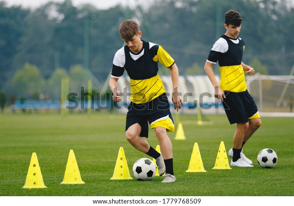 Boys on soccer football training. Young\
players dribble ball between training cones. Players on football\
practice session. Soccer summer training\
camp