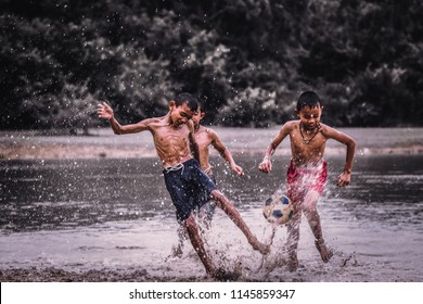 Boys Play Football On A Muddy Waters