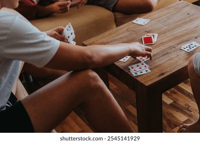 Boys playing cards game around a wooden table at home. A fun and engaging activity with friends. - Powered by Shutterstock