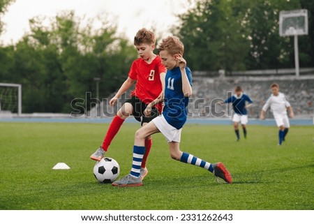 Boys playing football game on a school tournament. Football soccer match for children. Dynamic, action picture of kids competition during playing football