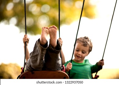 Boys Playing On A Swingset.