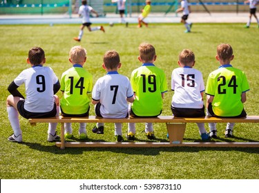 Boys Playing Soccer. Young Football Players. Young Soccer Team Sitting On Wooden Bench. Soccer Match For Children. Young Boys Playing Tournament Match. Youth Sports Club Players