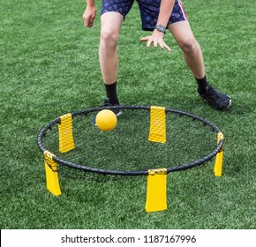 Boys Are Playing Spike Ball On A Green Turf Field