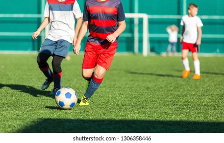 Boys in red white sportswear running on soccer field. Young footballers dribble and kick football ball in game. Training, active lifestyle, sport, children activity concept  - Shutterstock ID 1306358446