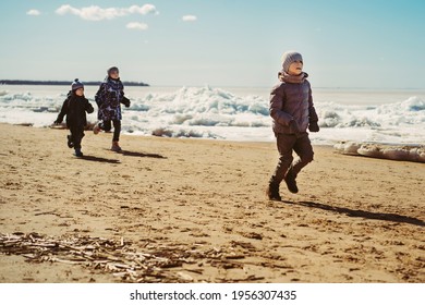 Boys Running Along Beach Of Finland Gulf Covered With Ice. Image With Selective Focus