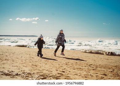 Boys Running Along Beach Of Finland Gulf Covered With Ice. Image With Selective Focus