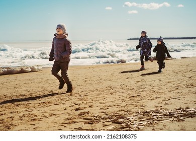 Boys Running Along Beach Of Finland Gulf Covered With Ice. Image With Selective Focus. 