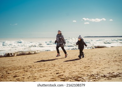 Boys Running Along Beach Of Finland Gulf Covered With Ice. Image With Selective Focus. 