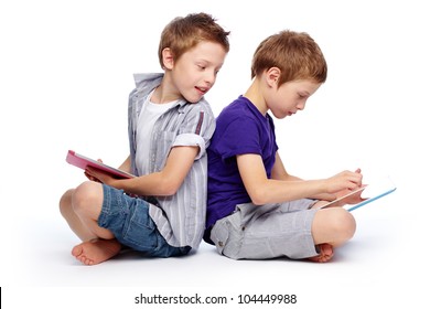 Boys sitting back to back using hi-tech digital pads - Powered by Shutterstock