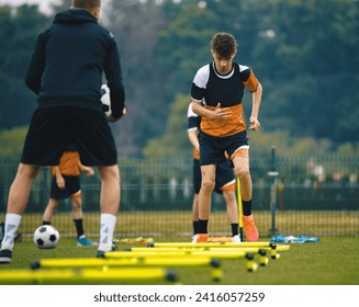 Boys' Soccer Practice Camp. Teenage boys in football training with a young coach. Teenagers on football camp. Junior-level athletes jump over hurdles. Soccer strength and coordination skills - Powered by Shutterstock