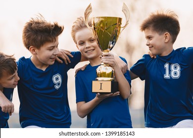 Boys Sports Team Celebrating Victory. Happy Children Holding Golden Trophy. Kids Football Team Raising Winners' Cup.  Youth Sports Success