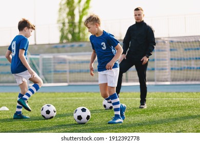 Boys Training Soccer Outdoor Witch School Coach On Summer Sunny Day. Happy Kids Running Classic Football Balls On Grass Training Field