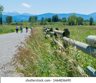 Bozeman, Montana/USA -July 20, 2019 : 4 People Walking And Biking Along A Rural Gravel Path On A Sunny Summer Day With Majestic Mountains In The Distance