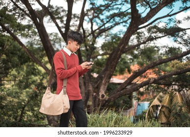 A BPO Or Call Center Employee Plays Video Games While Taking A Walk To The Office. Distracted And Not Paying Attention To The Sidewalk. Potentially Dangerous Habit.