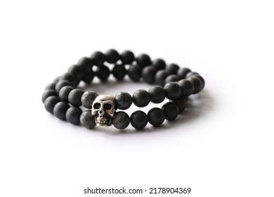 Bracelet made of natural black stone with skeleton charm on white background