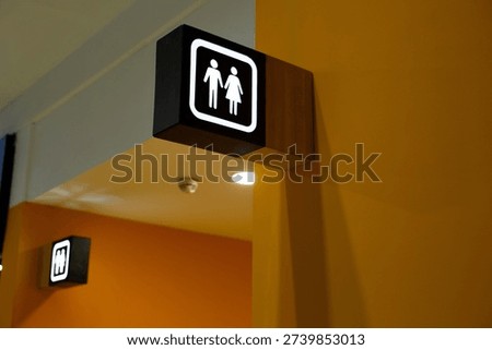 Bracket panel with illuminated sign featuring gender symbols for men and women. Designating public restroom. Entrance to wc in shopping center. Separation of men and women