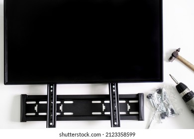 Bracket for wall mounting computer monitor or TV, electric screwdriver, hammer, mounts and monitor screen on white background. Concept of wall mounting TV or computer monitor in the interior. Close-up