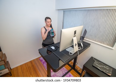 A Braded Woman Working Out From Her Home Office Gym, At Her Ergonoic Stand Up Desk