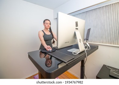 A Braded Woman Working Out From Her Home Office Gym, At Her Ergonoic Stand Up Desk