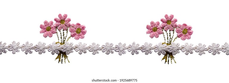 Braid, ribbon, lace from white embroidered flowers. In the middle are bouquets of pink flowers. Isolated on white background.