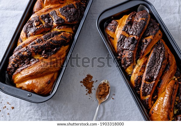 Braided cake with row\
cocoa in black baking tin molds. Yeast-risen dough twisted krantz\
cake, two loafs. 
