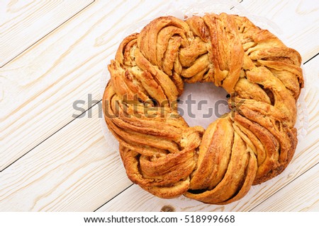 Braided cinnamon roll cake on wooden background.