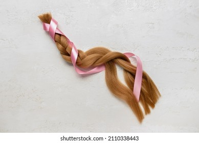 Braided Red Hair For Donation With Pink Ribbon On Light Background