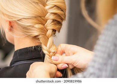 Braiding Braid. Hands Of Female Hairdresser Braids Long Braid For A Blonde Woman In A Hair Salon