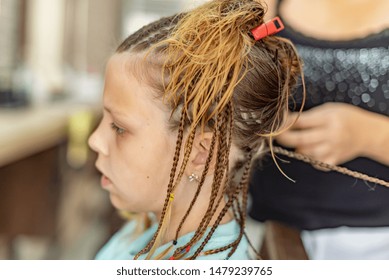 braiding a lot of braids for girl in the beauty salon
