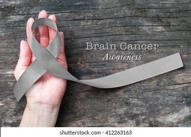 Brain cancer awareness, grey ribbon on helping hand