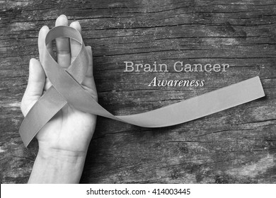 Brain cancer awareness with grey ribbon on helping hand