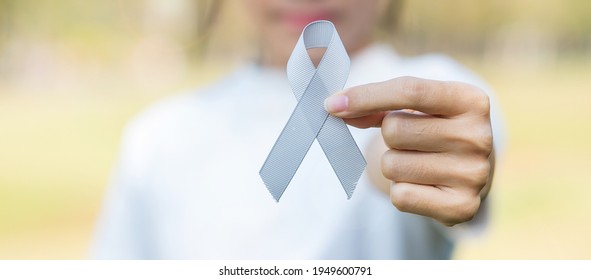 Brain Cancer Awareness month, woman hand holding grey color Ribbon for supporting people living. Healthcare and World cancer day concept