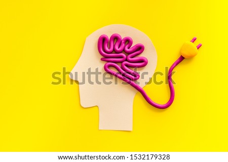 Brain charging and mental rest. Plug and cable leads to plastiline meanders on yellow background