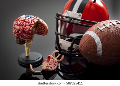 Brain Damage And Sports Injury Concept With Damaged Brain Model, American Football Helmet And A Ball, Illustrating CTE (Chronic Traumatic Encephalopathy) A Syndrome Caused By Repeated Concussion