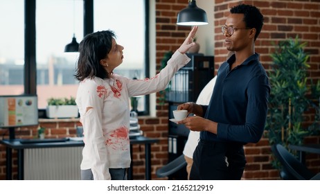 Brain Dead Zombie Woman Touching Businessman While Discussing. Doomsday Survivor Talking With Dangerous Dead Walking Corpse Having Bloody And Deep Wounds In Office Workspace.