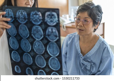 Brain disease diagnosis with medical doctor diagnosing elderly ageing patient neurodegenerative illness problem seeing Magnetic Resonance Imaging (MRI) film for neurological medical treatment