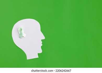 Brain Paper Cutout With Green Ribbon On Green Background With Copy Space. Mockup For World Mental Health Day