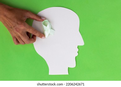 Brain Paper Cutout With Green Ribbon On Green Background With Copy Space. Mockup For World Mental Health Day