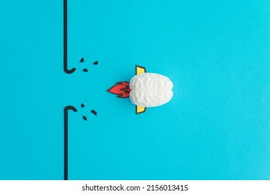 Brain rocket breaking through black wall obstacle on blue background minimal style. Concept of breakthrough for new idea, innovative and successful goal in business financial.
